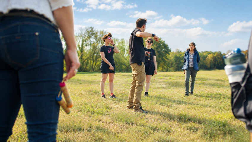 Exercice collectif avec des baguettes de sourcier pendant une séance en plein air.