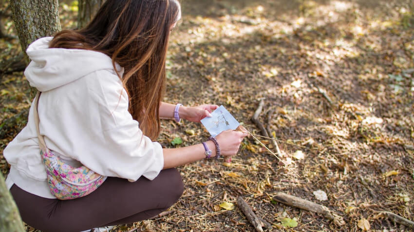 Participante utilisant des Baguettes Sensitives pendant un exercice en forêt.