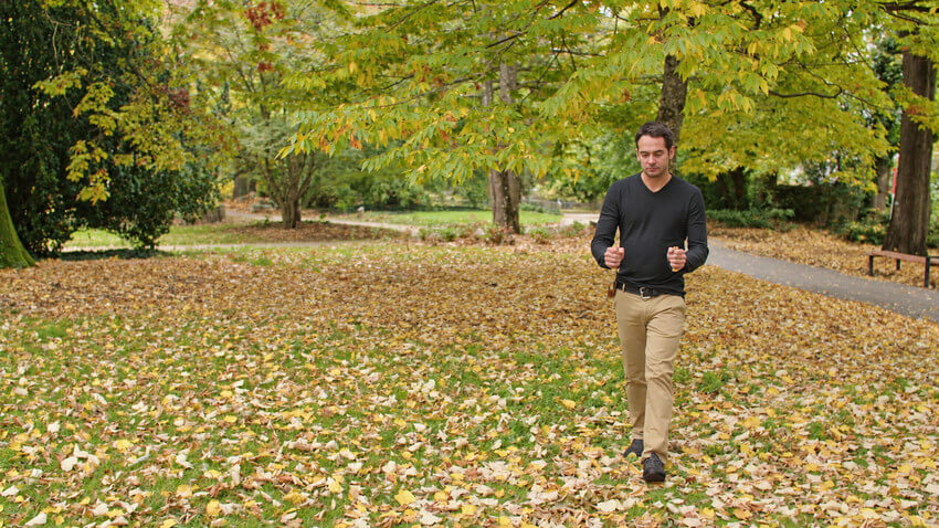 Marche de radiesthésie avec des baguettes de sourcier dans un parc aux couleurs d’automne.